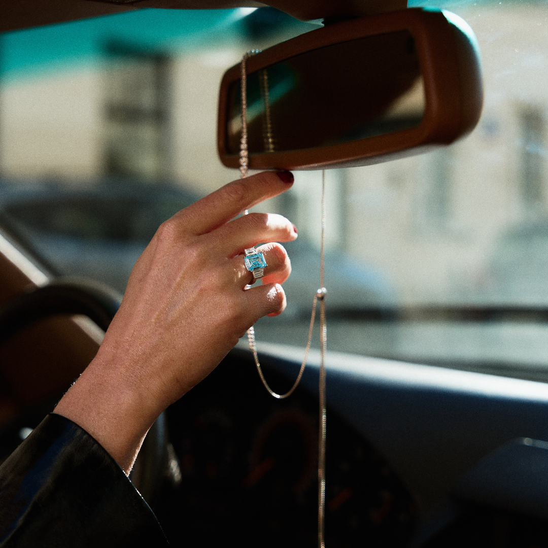 Hand with a ring adjusting a car's rearview mirror
